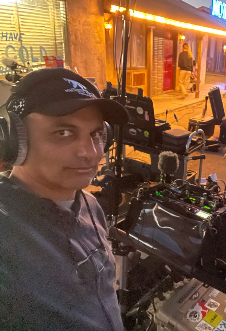 Camera operator working with professional equipment in a dimly lit TV studio setting.